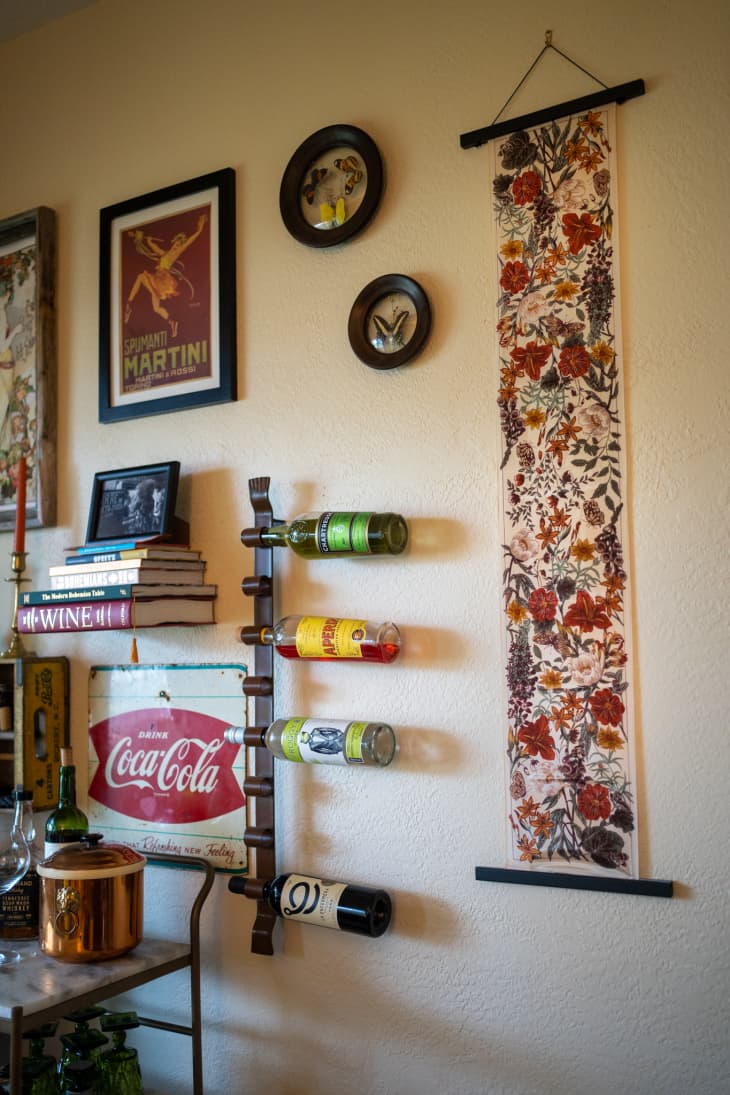 A silk scarf on a wall next to bottles and art