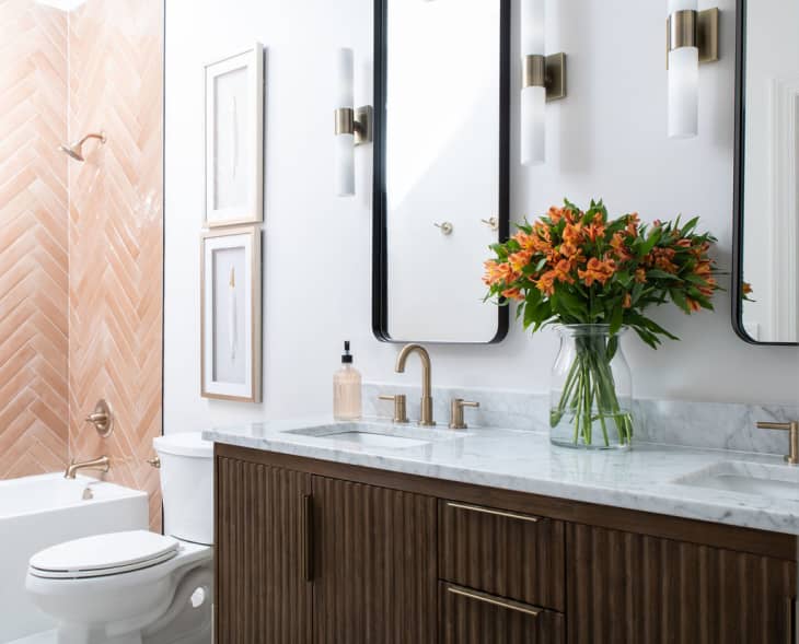 Bathroom designed by Marie Cloud of Indigo Pruitt with a wooden vanity, white countertop and coral shower surround