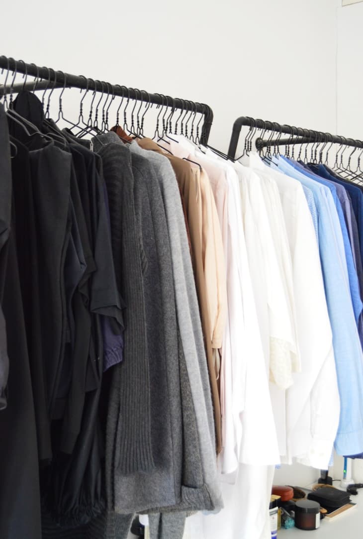 Clothes hanging on metal hangers on a black closet frame