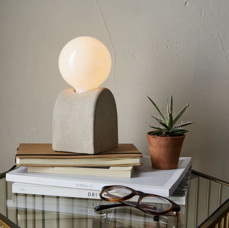Ceramic table lamp that looks like a lightbulb on a mound of sand
