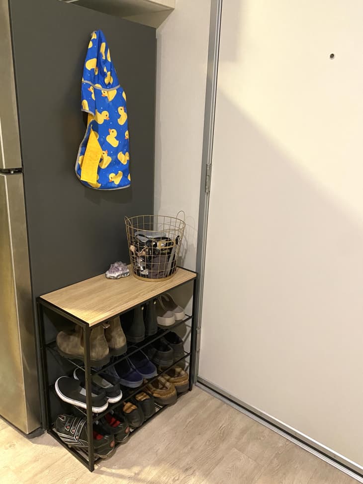 Shoe rack beside entryway in small apartment.