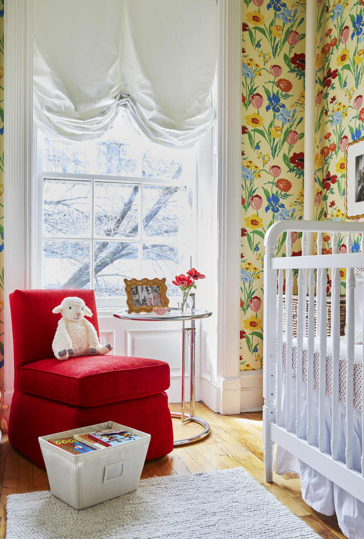Nursery with bold red slipper chair and yellow floral wallpaper