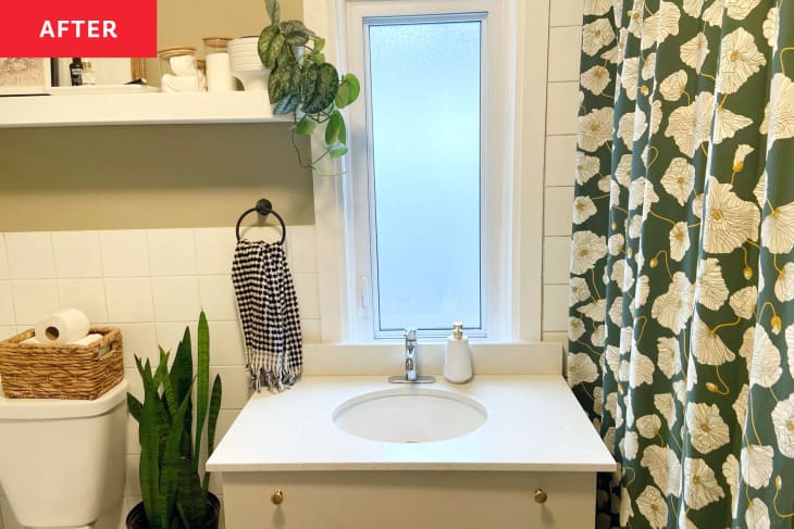 Newly renovated bright bathroom with a light colored vanity and green floral shower curtain.