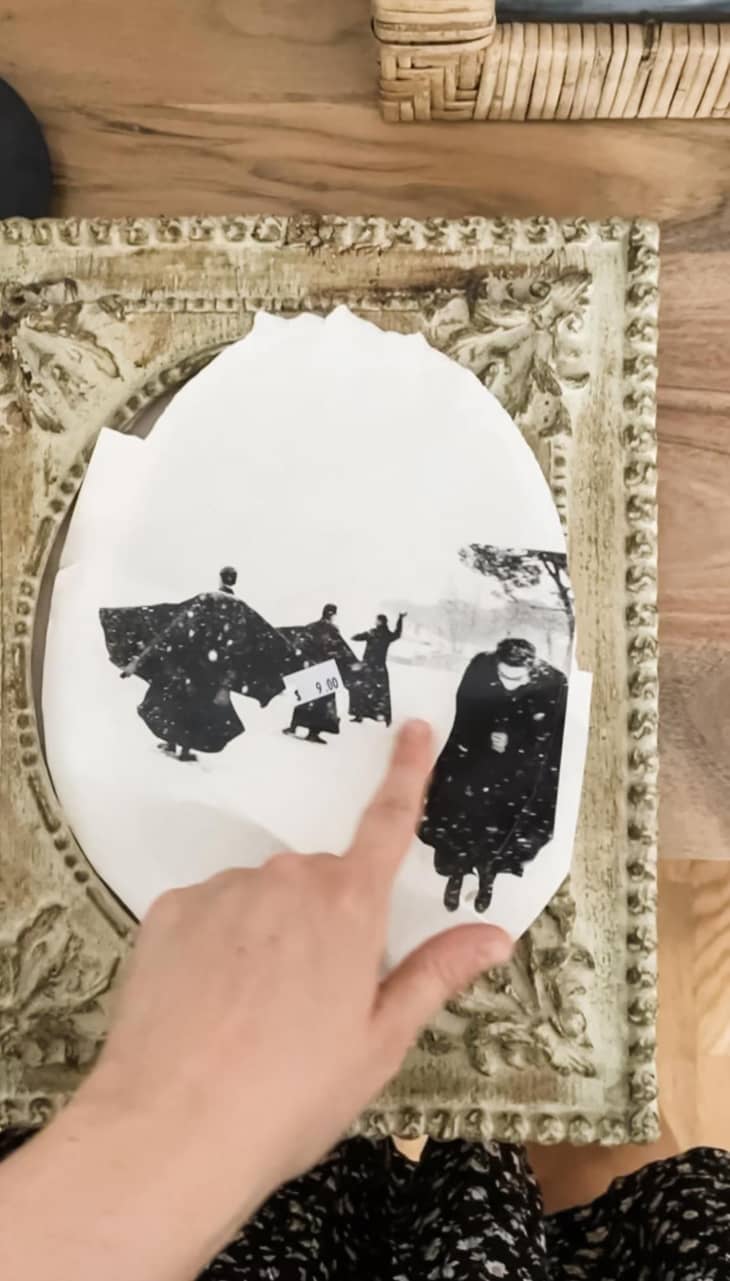 Someone pointing to vintage photo in a frame.