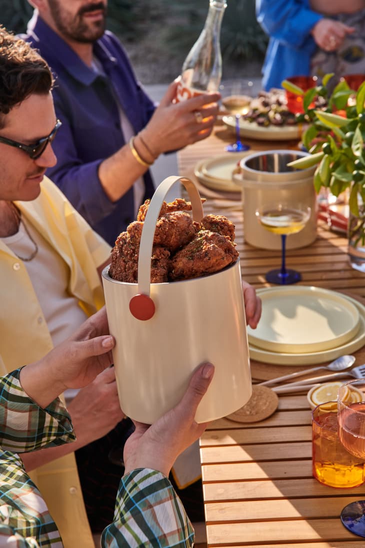 Molly Baz x Crate &amp; Barrel tools launch: someone at an outdoor lunch passing a bucket of fried chicken