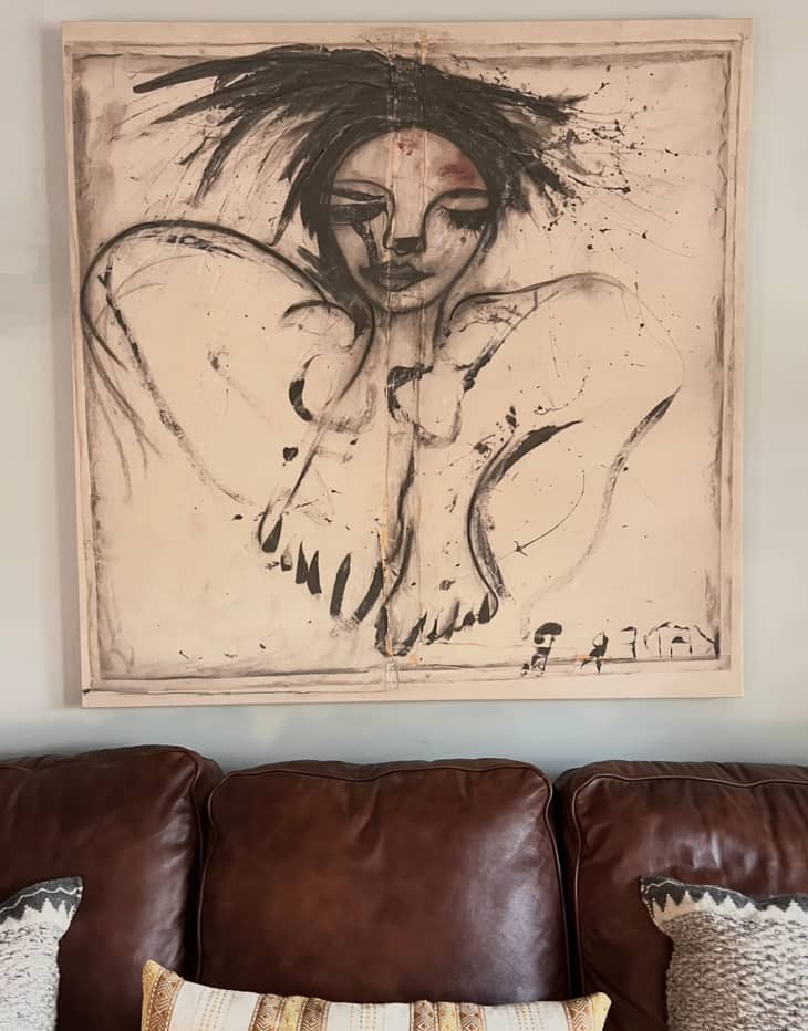 Charcoal drawing above leather sofa.