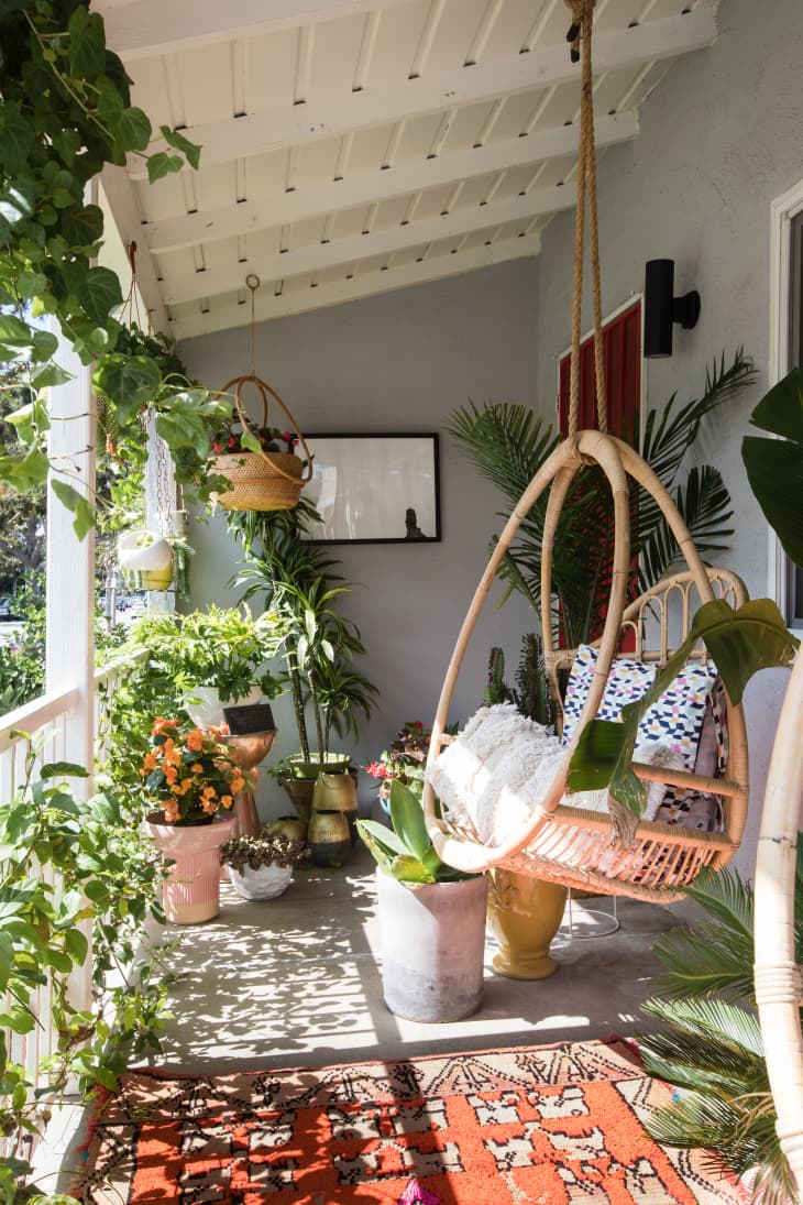 a balcony garden with lots of greenery, a bold rug, and a hanging chair