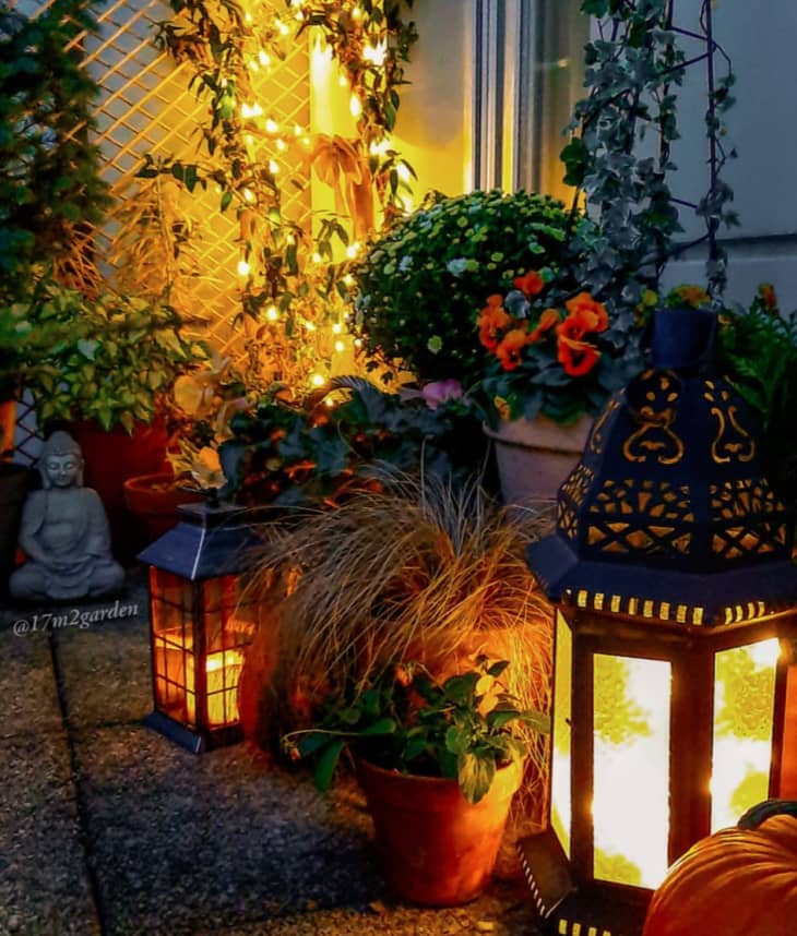 lit lanterns on a balcony garden with string lights in the background
