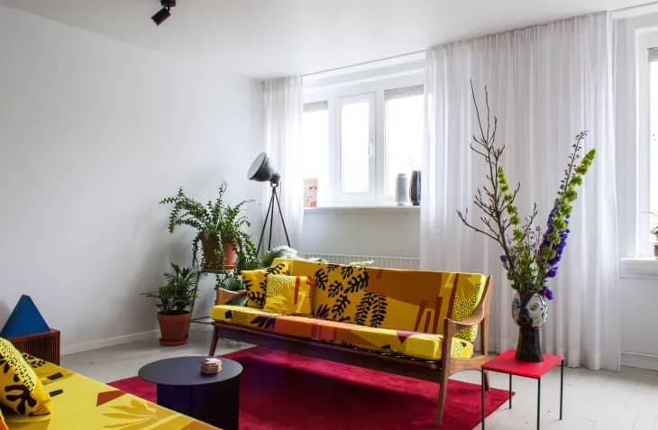 small yellow patterned couch on top of a red rug in a white room