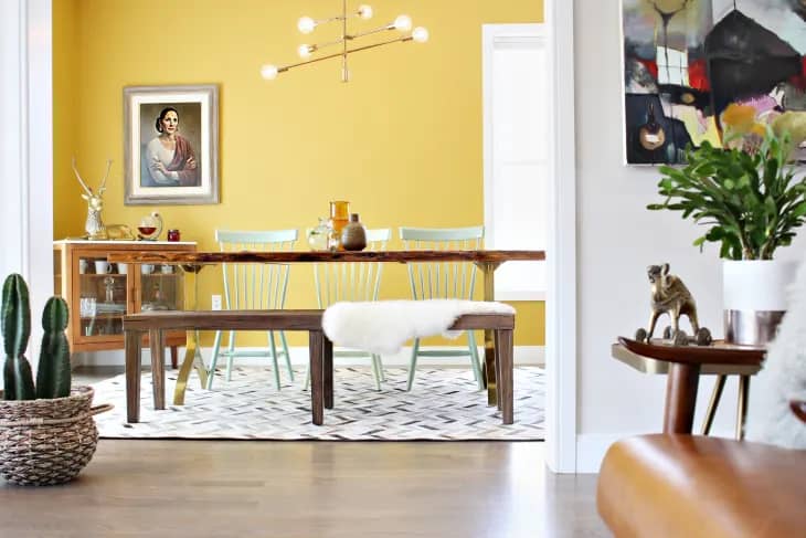 yellow wall behind a natural wood kitchen table and chairs