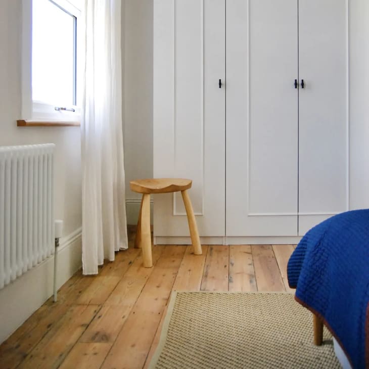 a simple bedroom with light wood floors and an IKEA PAX wardrobe with moulding attached