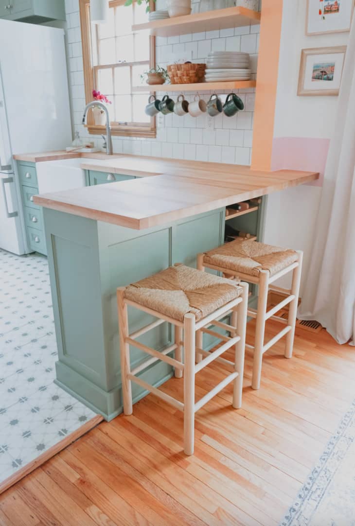 mint green cabinets against a light wood floor and light wood countertops