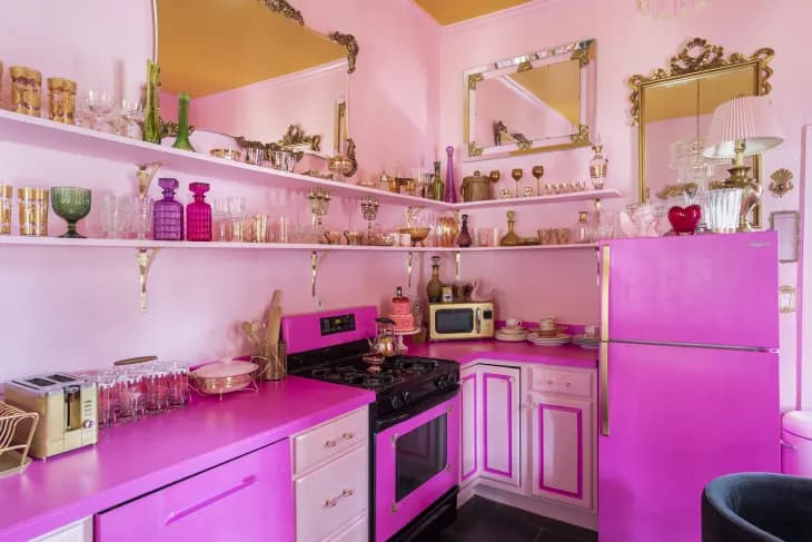 monochrome pink kitchen with pastel walls and fuchsia fridge, countertops, and oven with gold accents