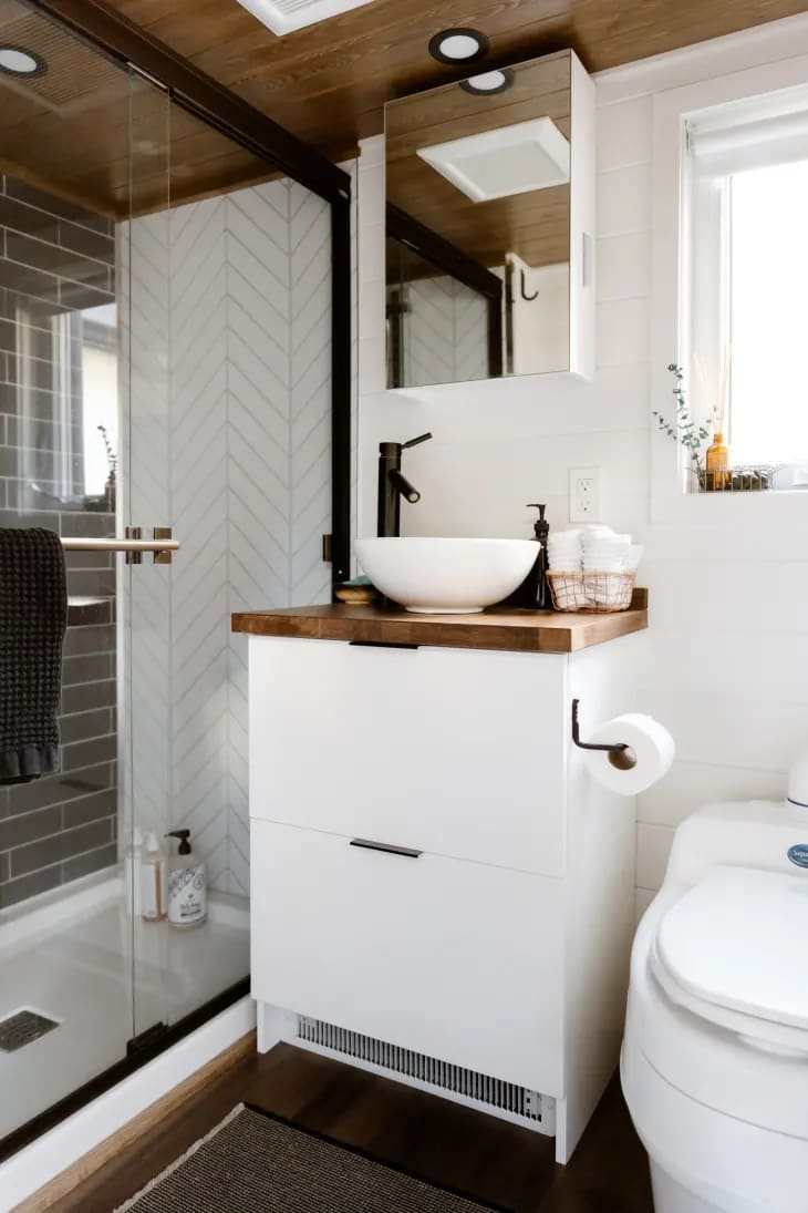 a white bathroom with white walls, cabinetry, and shelving, but with wooden countertops and ceilings