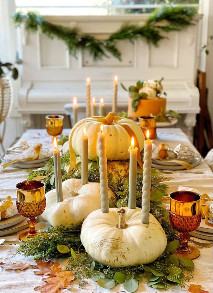 holiday table with centerpiece featuring white pumpkins as candle holders