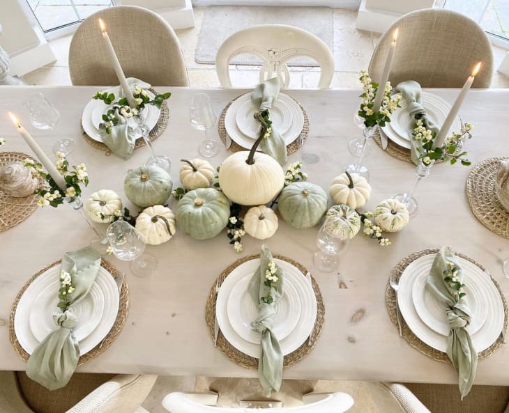 White table with white and green pumpkin centerpiece, candles