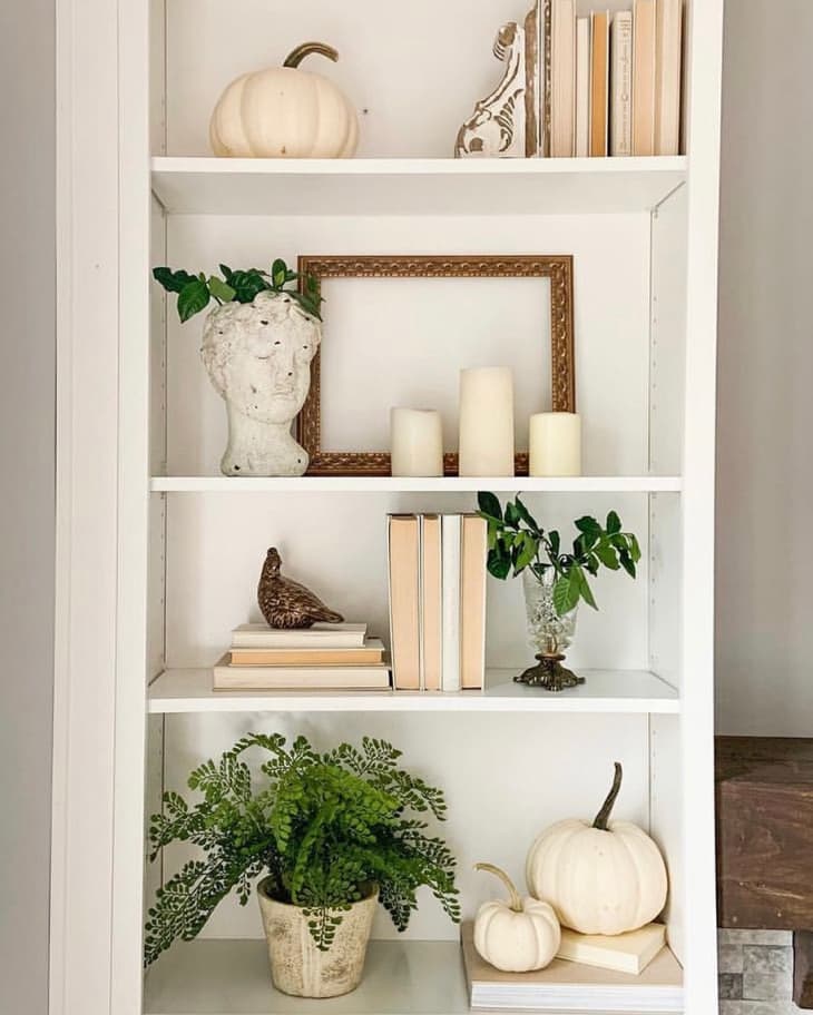 bookshelves with books, decor, white pumpkins