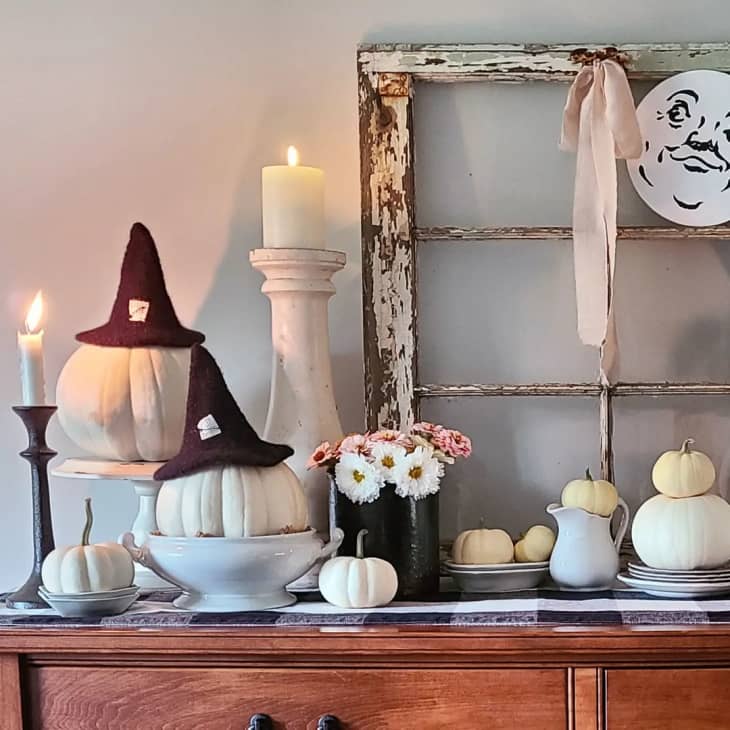 white pumpkins with black witch hats, lit candles, flowers, decor accents