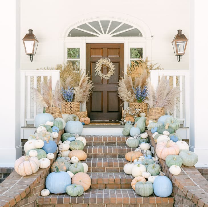 Pumpkins of various sizes and colors decorate front entry of home.