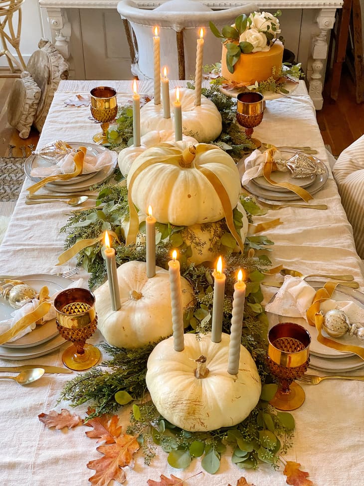 White pumpkins line tablescape with eucalyptus garland and taper candles.