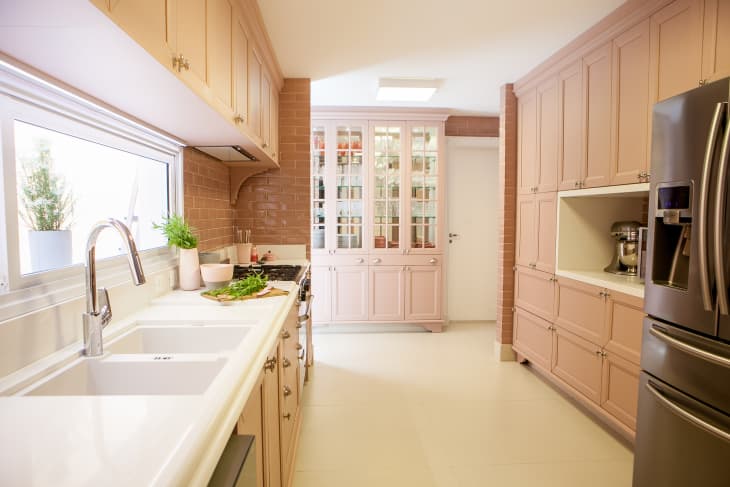 Kitchen with blush pink cabinets and drawers, cream floor, white counters, large blush pink hutch