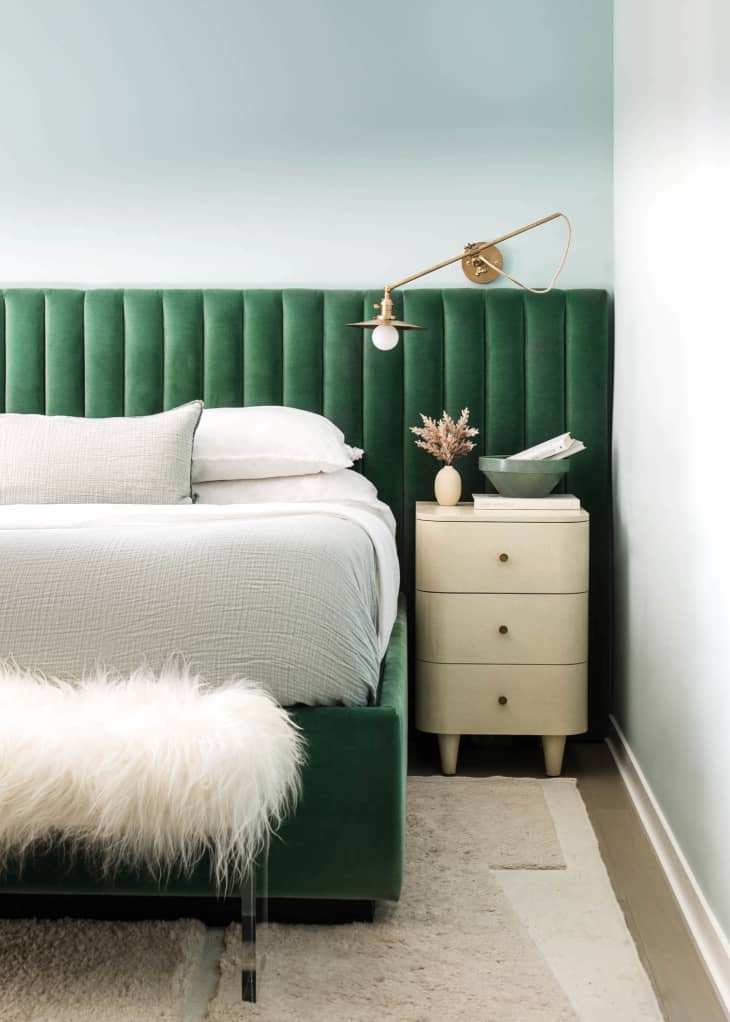 Bed with green velvet headboard, bench with shag throw, cream nightstand