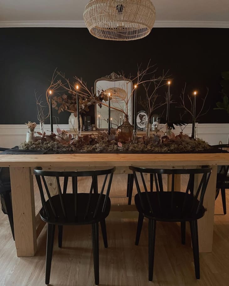 Dining room table with large dried-leaf runner and black candles
