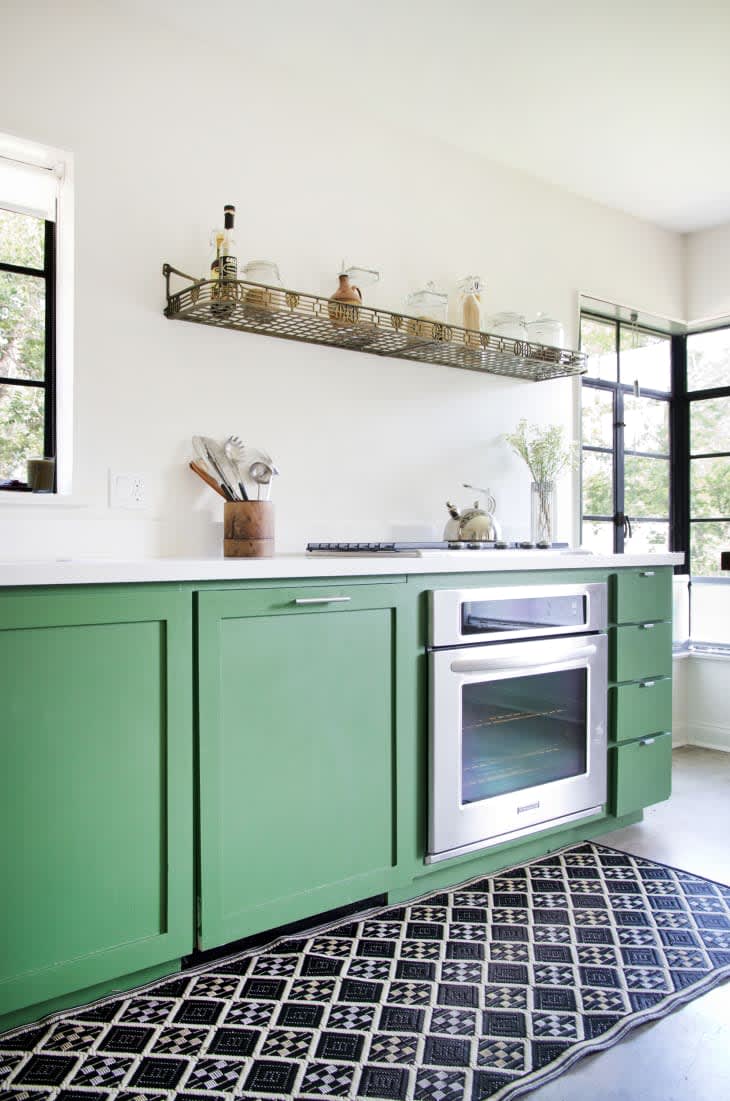 Green kitchen cabinetry with a black and white graphic runner