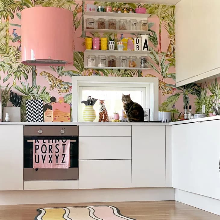 a Scandi-style kitchen with pink wallpaper patterned with jungle cats and tropical plants
