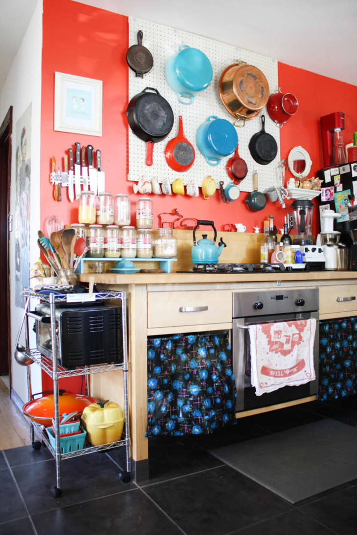 a kitchen with a pegboard holding pots and pans