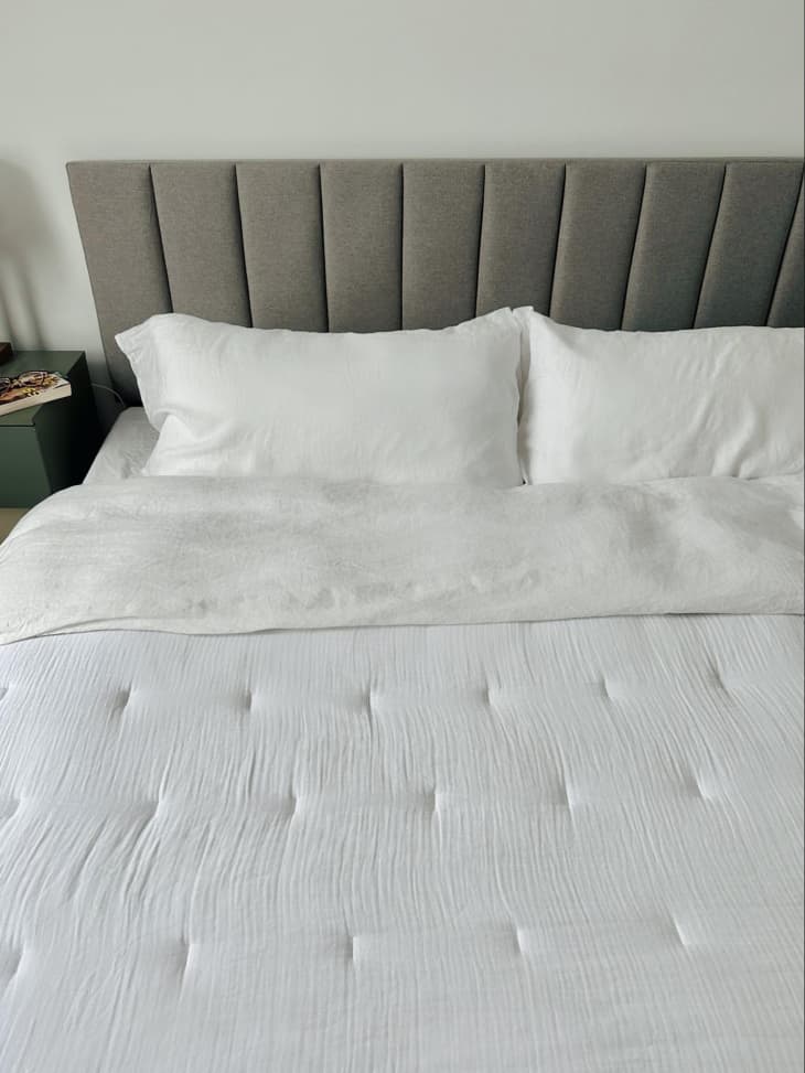 A neatly made bed with white bedding.