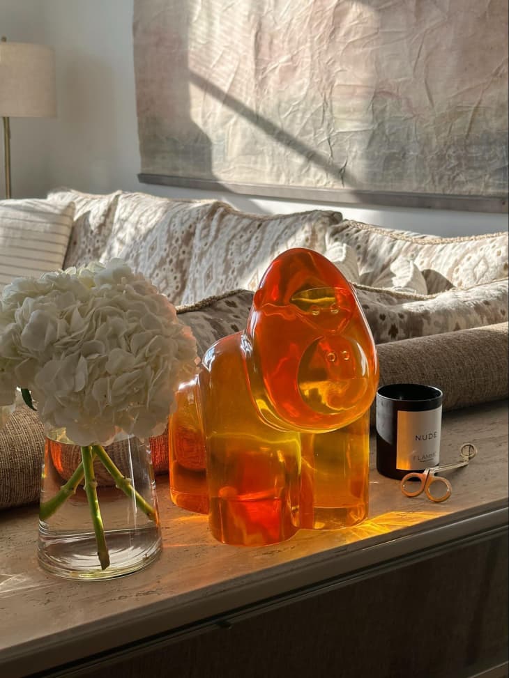 Glass decorative gorilla and candle and flower arrangement on the surface.