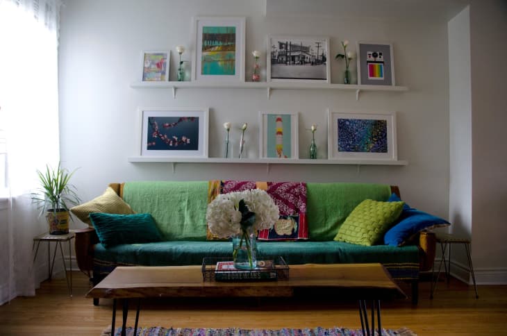 a living room with shelves holding art behind the couch