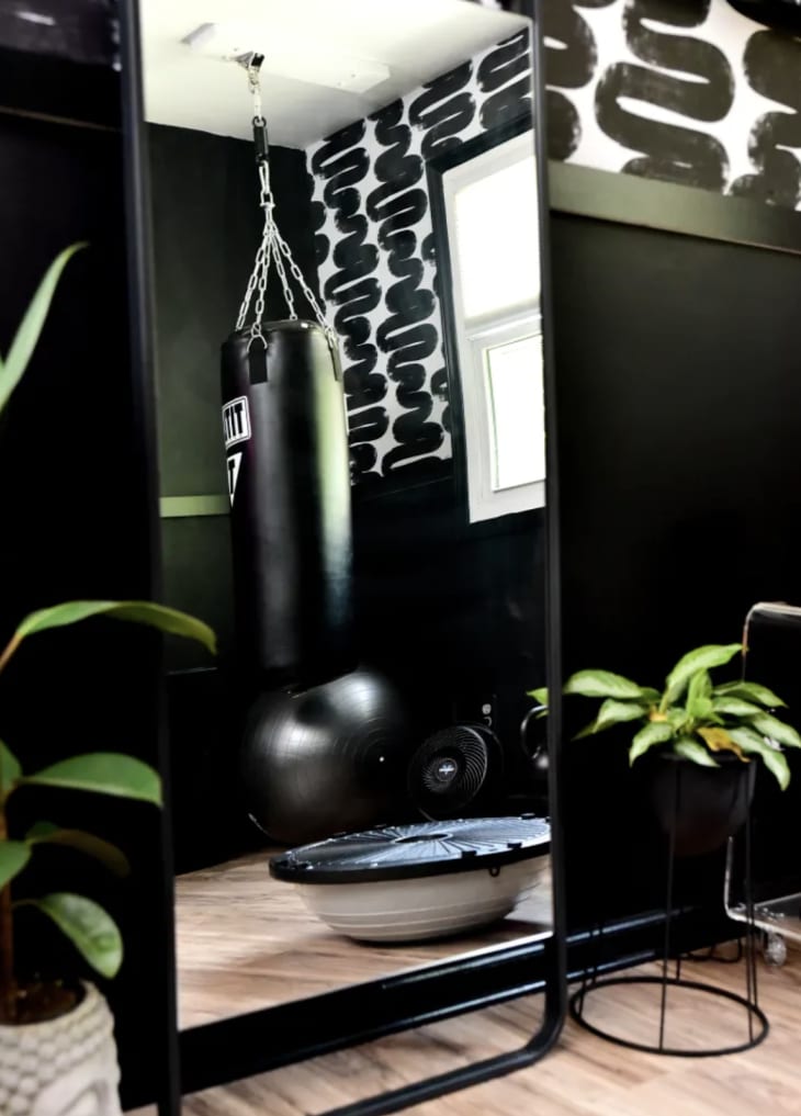 black mirror leaning on black wall with squiggly detail on half wall and black punching bag