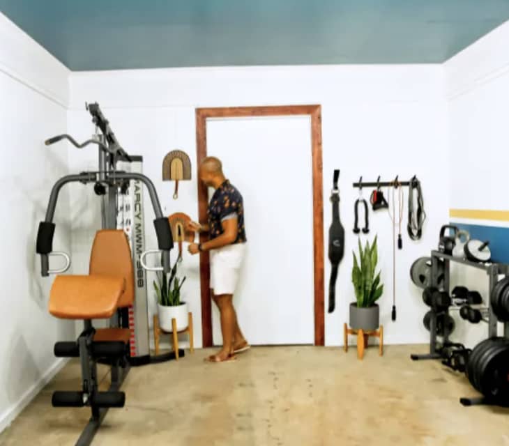 small white room with work out equipment on walls and one large machine, blue ceiling