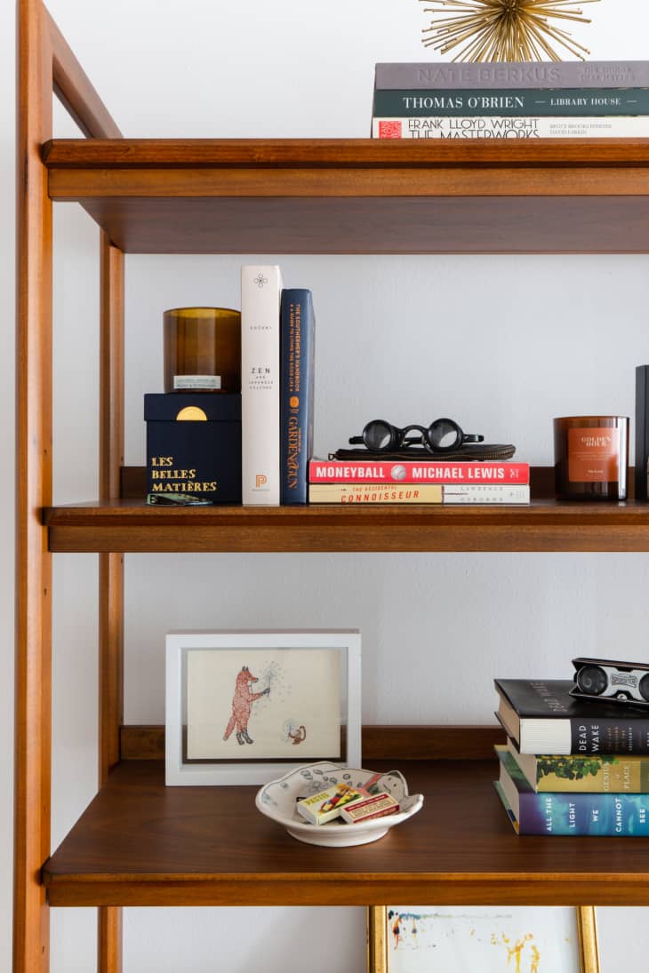 dark wood book shelf with books, art and knickknacks placed on shelves in designed way