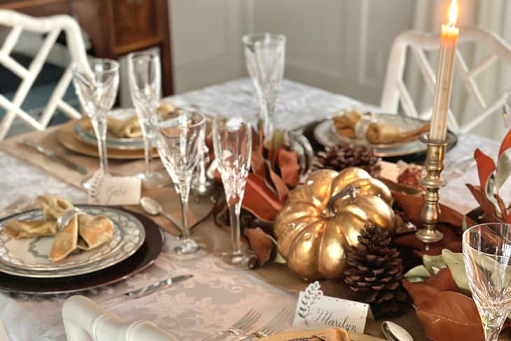 table setting for holiday party with golden pumpkins and candle sticks