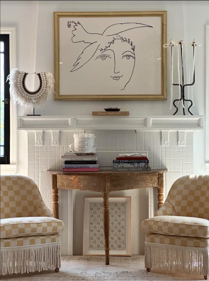 White brick fireplace with art above it and a console table in fron to fit