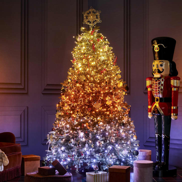 Life-sized nutcracker next to a Christmas tree with warm gold to cool silver ombre effect lights from Twinkly