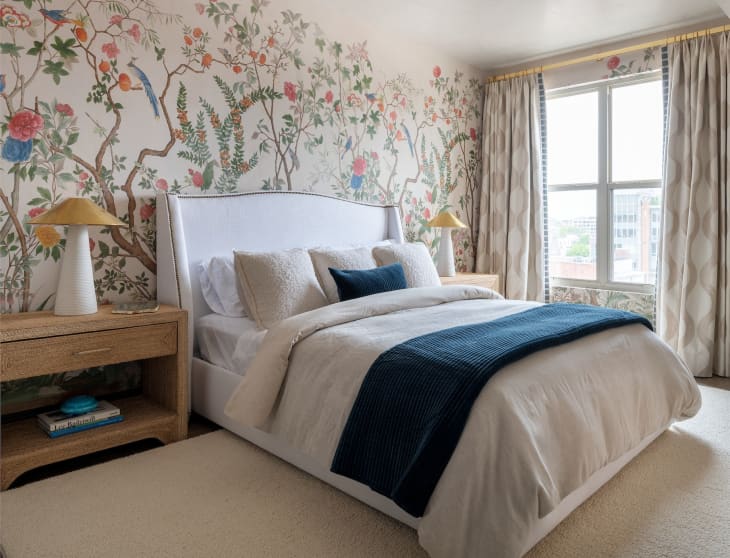 Bedroom with botanical wallpaper and bed with boucle pillows