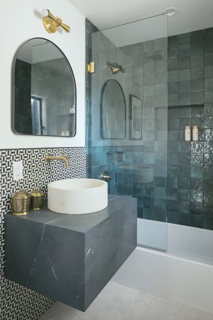 bathroom with blue tiled shower and black and white patterned wall tile