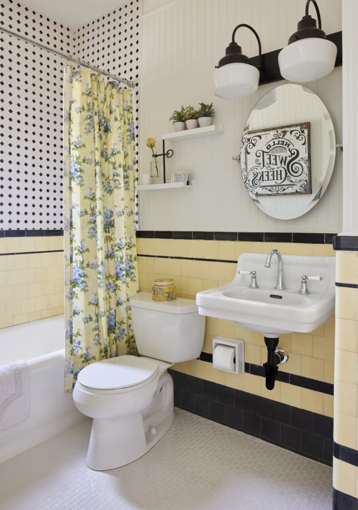 Bathroom with pale yellow and black tile, black and white tile shower, and pale yellow floral shoer curtain