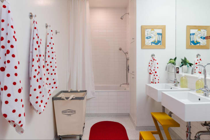 White bathroom with pops of red in the bath mat and towels