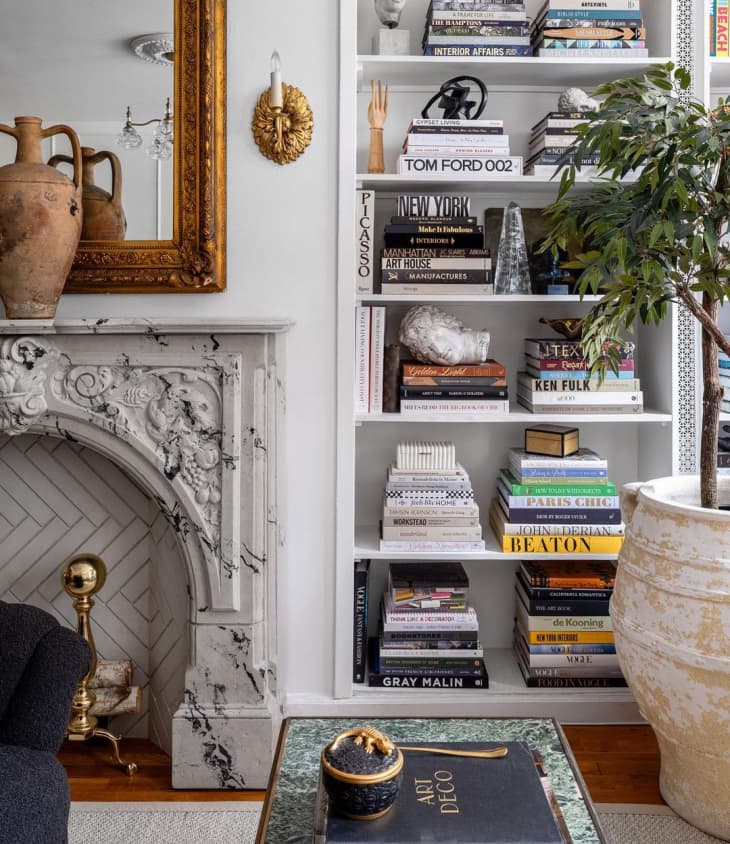 white bookshelves with stacks of books next to fireplace