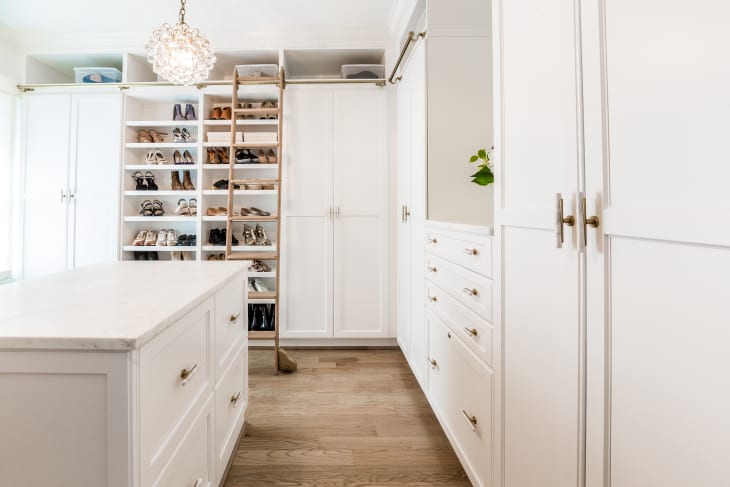 Light brown wooden floors in large white walk in closet.