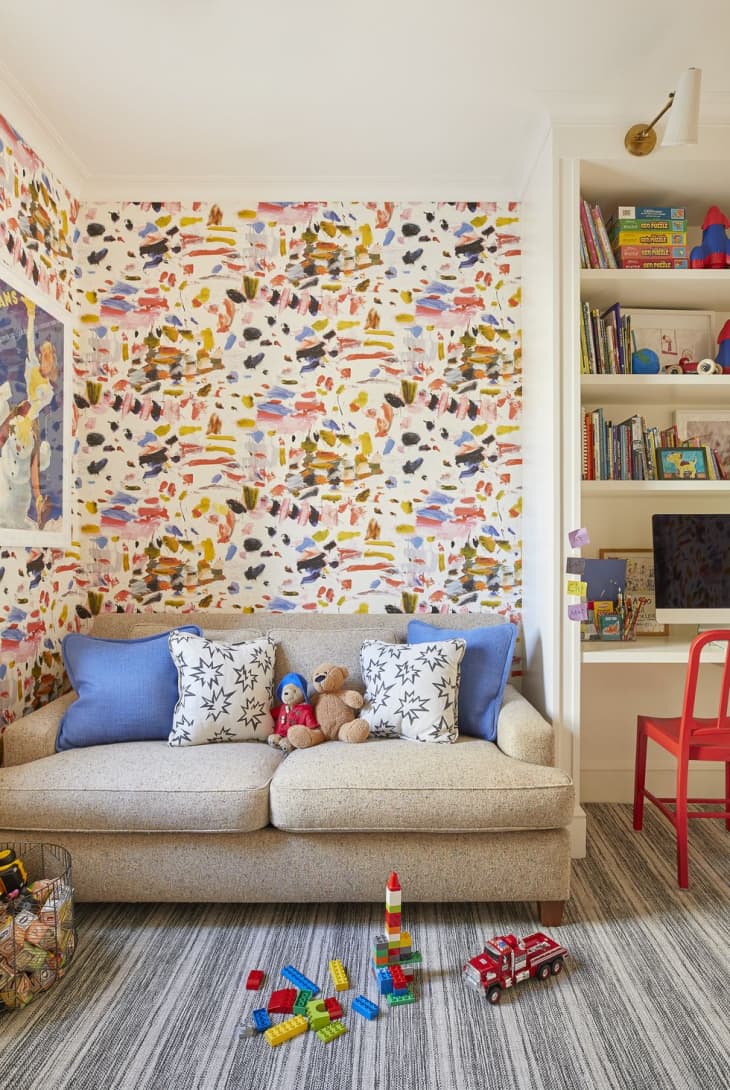 Colorful wallpaper behind beige sofa kids room