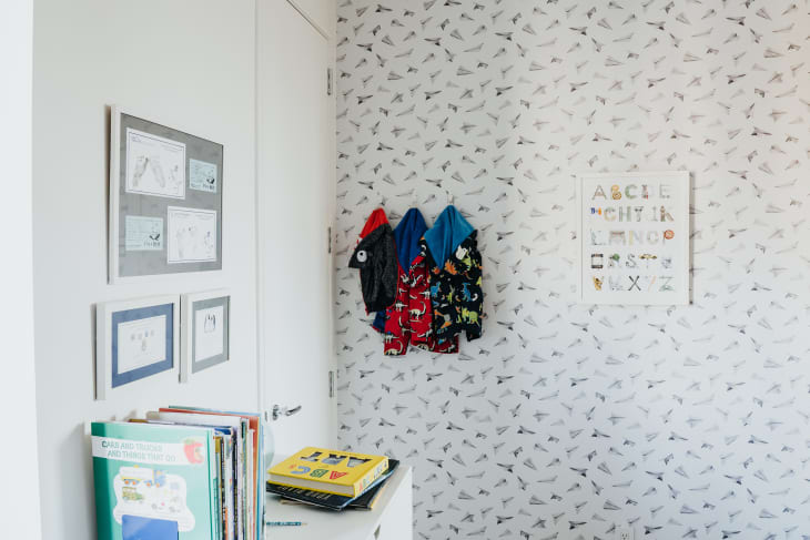 Boys' bedroom in NYC. Lots of white, white walls, white shelves, white furniture, with pops of color: red bed linens, patterned throw pillows, etc