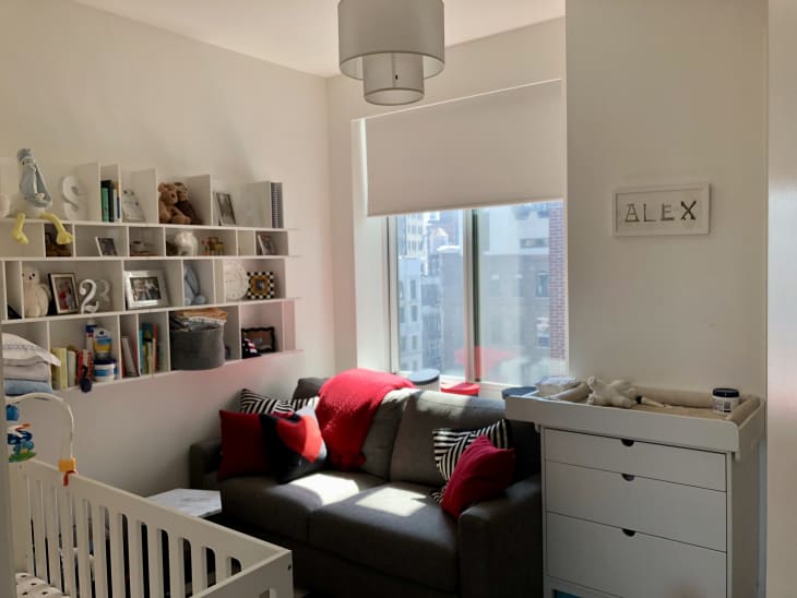 Boys' bedroom in NYC. Lots of white, white walls, white shelves, white furniture, with pops of color: red bed linens, patterned throw pillows, etc