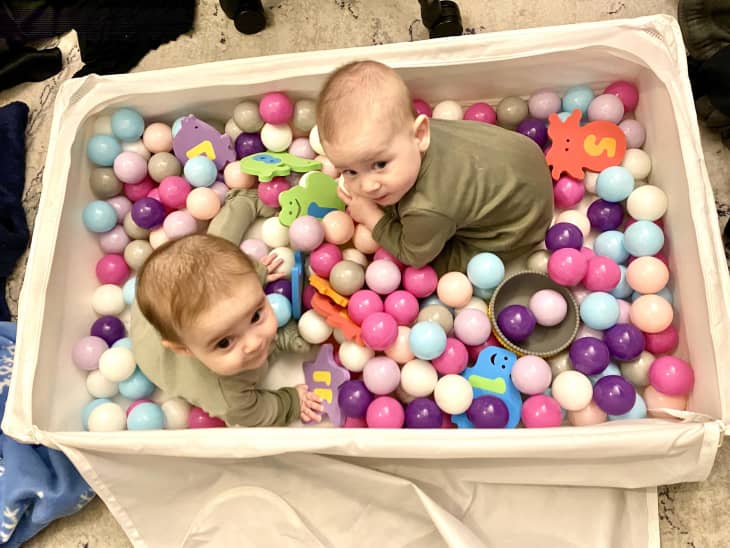 Babies playing in homemade ball pit that's been crafted from an IKEA STUBB storage case