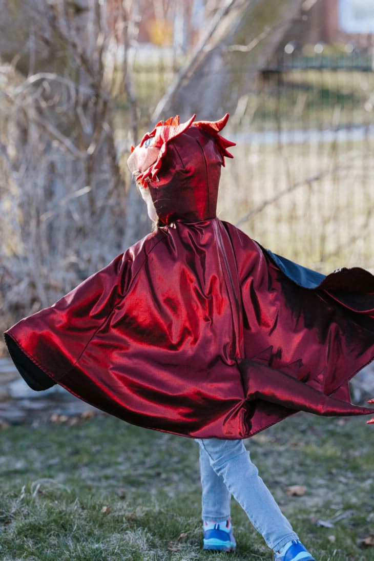 A kid in a dragon cape costume